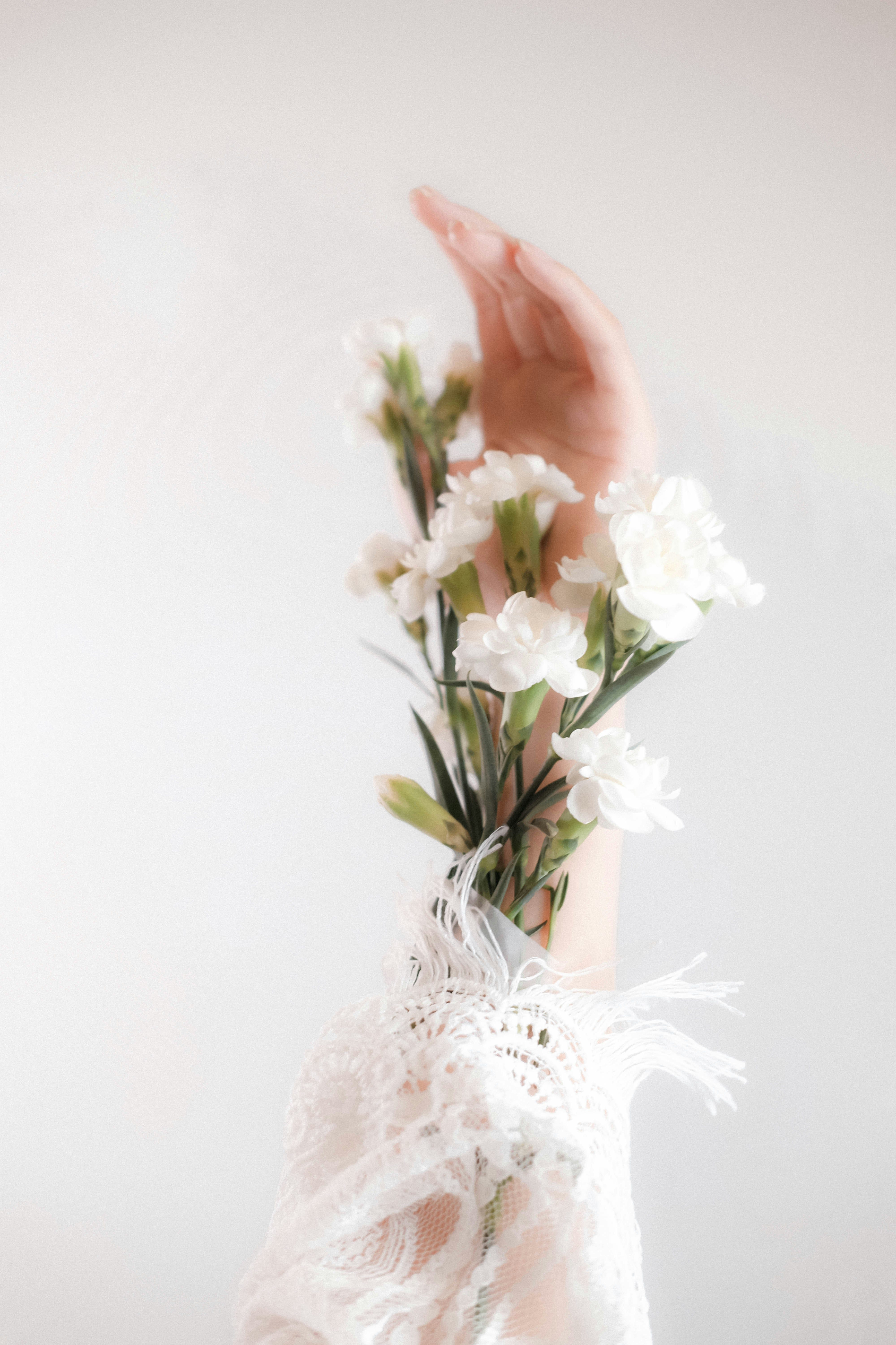 Photo by Linh Le on Unsplash A hand gently holding flowers wrapped in soft lace, reflecting quiet beauty and grace.