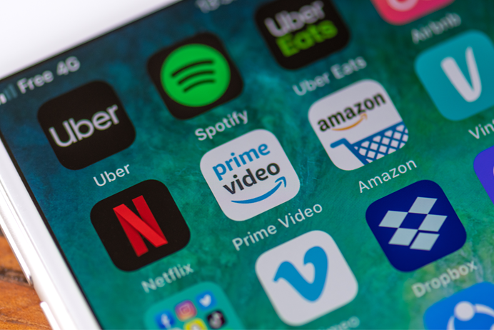 Smartphone screen displaying various subscription service app icons like Netflix, Spotify, and Adobe