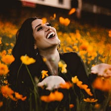 Smiling woman in field of orange flowers.