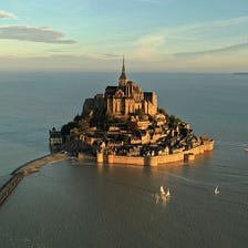 An aerial view shows the iconic Mont-Saint-Michel surrounded by sea at sunrise, during the highest…