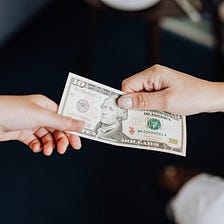 Hands exchanging a ten dollar bill