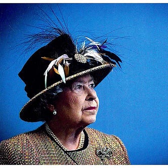 Portrait of Queen Elizabeth II ca. 2012, appearing pensive against a blue background, wearing a feathered hat