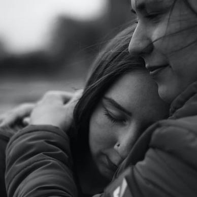 Two people embracing comforting one another.