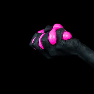 a hand painted black squeezing bright pink slime between its fingers.