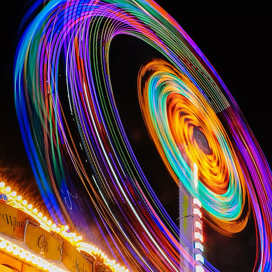 An image of a spinning amusement ride, circle shaped, flowing around in a circle on the side of use. The aperture is slowed to allow the colors of the ride to blend and bleed in the circle motion. The colors are various and multiple to emphasis use within this philosophy blog post.