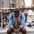 A thinking man sitting in front of a vibrant city scene.