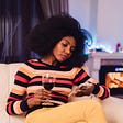 Bored woman looking at her phone holding a wine glass.