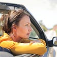 woman in car on road, looking into the distance