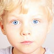 The image of a blond boy with blue eyes, apparently sad, possibly after the separation from his parents in the morning at preschool.