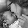 Black and white photo of a mother kissing her infant.