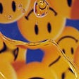 A photo of water droplets on glass with a reflection of upside down smiley face icons in the background.