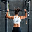 A woman lifting weights with her back to the camera.
