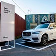 A photo of an Uber self driving car on display with a sign that reads “Self-Driving Car” to the left.