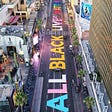An aerial photo, presumably taken by drone, of protests in LA. “ALL BLACK LIVES MATTER” is painted on the road.