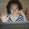 Senior woman waving hi to the Zoom call with a restrained expression.