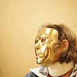 Picture of a woman wearing a golden mask which hides her features.