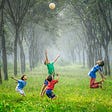 4 children playing ball in a wood