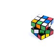 An unsolved Rubik’s cube on a blank, featureless surface.