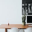 A plant on a wooden table with calendar for productivity