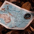 A world map with a compass sitting on top of it