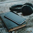 Notebook, phone and a pair of headphones.