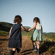 two girls walking hand in hand n nature