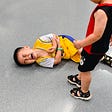 young kid on the ground grabbing his elbow while grimacing in pain