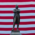 Bronze statue of Thomas Jefferson in front of U.S. flag