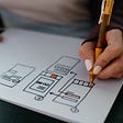 Person drawing an app mock up with pen and paper.