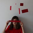 A lady in a red outfit is having a piece of paper blindfolded