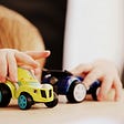 Toddler’s hands holding two toy cars