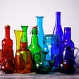 a collection of uniquely shaped glass bottles of different colors