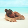 man lying face down on empty beach