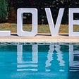 the word love reflected in a pool of water