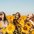 3 girls smiling in sunflower garden