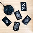 Black wireless charging pad on a wooden surface with playing cards