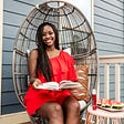Olay Regenerist Whip review and summer self care routine featured by top D.C beauty blogger, Alicia Tenise | Self Care Routine by popular D.C. lifestyle blog, Alicia Tenise: image of Alicia Tenise wearing a red ruffle dress and sitting in a rattan chair next to a end table that has a plate of sliced watermelon and a bottle of Olay Rengenerist Whip on it.