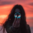 Woman holding a crystal ball in front of a sunset