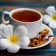Cup of cordyceps tea with dried cordyceps and flowers beside