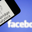 A phone with Cambridge Analytica’s logo over the background of the Facebook logo.
