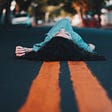 woman lying on double lines in center of empty road
