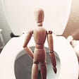 wooden doll standing in front of toilet