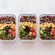 Three portioned, healthy meals with lots of vegetables sit on a counter.