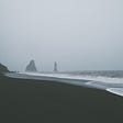 A beach, waves and a grey, foggy sky