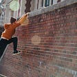 Person climbing up a brick wall