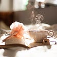 A pen, a book and glass of warm tea place on tablecloth in sunshine