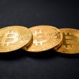 Three Bitcoin coins on a black background — Why is Bitcoin worth so much?