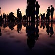 Silhouettes of people standing on a reflective surface