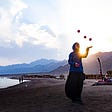 Woman juggling three balls on a beach