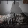 woman struggling to get to sleep figure tossing on bed with shadow of woman sitting upright unable to sleep